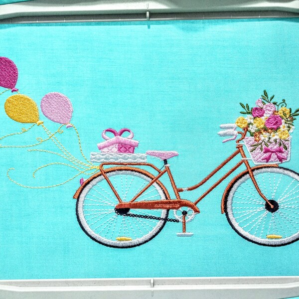 Bicycle With Flowers Machine Embroidery Design stitch-out: Embroidered design of a bicycle with flowers and balloons on a blue background
