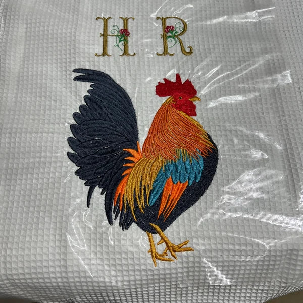 Golden Rooster Embroidery Design stitch-out: Embroidered rooster design on a textured fabric with initials 'HR'.