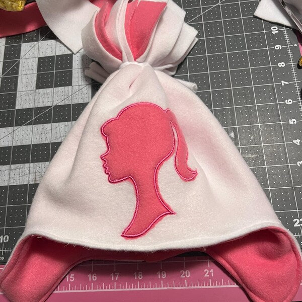 Girl Princess Head Silhouette stitch-out: Pink and white hat with a princess logo on a cutting mat