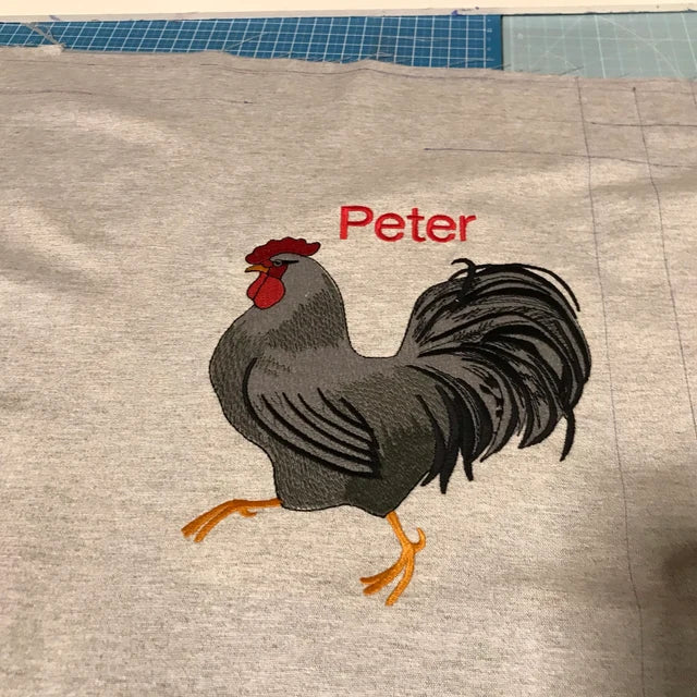 White Rooster Machine Embroidery Design stitch-out: White rooster stitched out on a piece of fabric